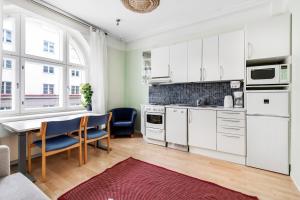 赫尔辛基Centrum - Lovely furnished Studio的厨房配有白色橱柜和桌椅