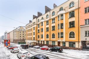 赫尔辛基Centrum - Lovely furnished Studio的一条雪 ⁇ 的街道,汽车停在大楼前