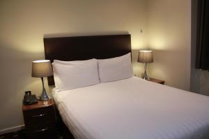 伦敦大广场服务公寓的一间卧室配有一张带两盏灯的大型白色床。