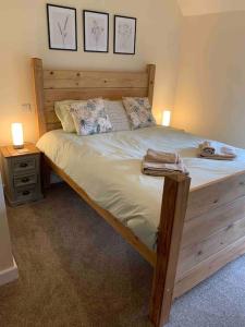 LongnorIvy House Farm, Near Longnor的一间卧室配有一张木床、两盏灯和两张桌子