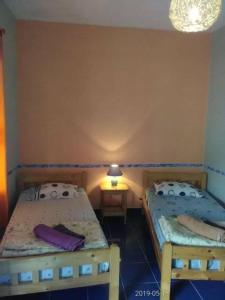 Vila Nova SintraDjabraba's Eco-Lodge的一张小房间内的两张床,配有一张桌子上的灯