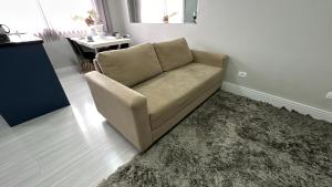 库里提巴08- Studio perfeito para família! Aconchegante e novo!的客厅里一张沙发,铺着地毯