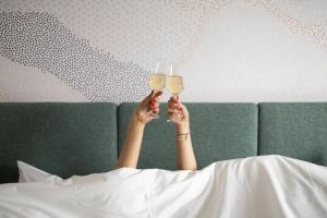 菲尔福尔德voco Brussels City North, an IHG Hotel的戴酒杯的女人躺在床上