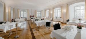 FischingenHotel Kloster Fischingen的一间设有白色桌椅的用餐室