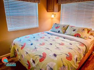 萨拉索塔Pinecraft Cottage Tiny Home的一间卧室配有一张带五颜六色的被子的床和窗户