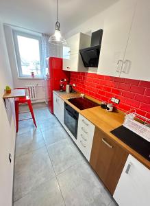 文盖尔斯卡－古尔卡Apartament 55的厨房设有红色的墙壁、白色的橱柜和一张桌子