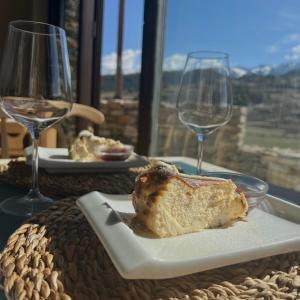 ToloríuLA HOSTERIA DE TOLORIU, el alt Urgell的桌上的盘子,上面有一块面包,还有两杯酒杯