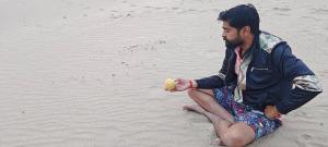 AuraiyaPachnad Camping And Water Sports Adventure的坐在海滩上拿着球的人