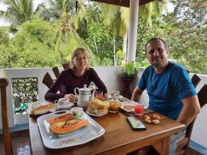 贝鲁沃勒Guest House Basilea的坐在餐桌上吃一盘食物的男人和女人