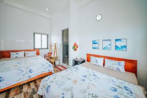 Cu Lao ThuNhà Nghỉ Phong Quỳnh - Đảo Phú Quý的卧室设有2张床和白色的墙壁。