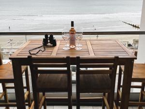 桑当25 Breakwaters - Pet friendly的一张木桌,配有一瓶葡萄酒和两杯酒