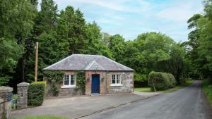 ClovenfordsEast Lodge at Ashiestiel的路边的石头房子,有蓝色的门