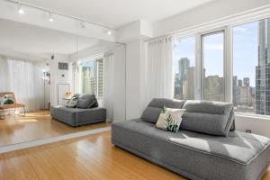 多伦多Modern 2-Bedroom Condo w Floor to Ceiling Windows的带沙发的客厅和部分窗户。