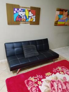 里贝朗普雷托Pousada Indi的客厅里一张黑色的沙发,有红色地毯