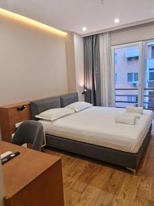地拉那Star Hotel Astir的一间卧室配有一张床、一张书桌和一个窗户。