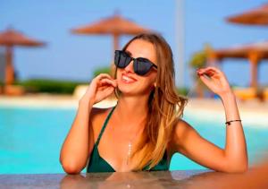赫尔格达Davinci Beach Hotel的坐在游泳池旁桌子旁的女太阳镜
