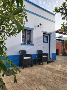 斯代塔维拉Monte da Caldeirinha的蓝色和白色的建筑,配有椅子和窗户