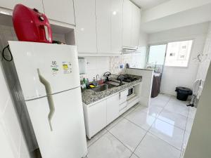 帕图斯迪米纳斯207- APARTAMENTO de 2 QUARTOS no ALTO CAIÇARAS的厨房配有白色橱柜和白色冰箱。