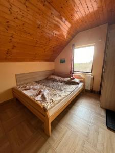 Mala RemetaFruškogorska Lugarnica的木天花板的客房内的一张床位