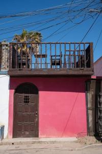 罗萨里托Be steps away from the beach - Downtown Rosarito的一座粉红色的建筑,上面设有一个阳台