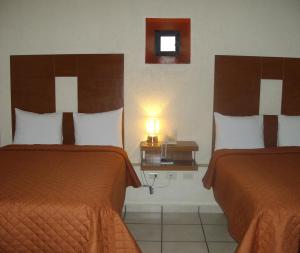 普埃布拉Hotel Casa de Oración San José的酒店客房设有两张床和一张带台灯的桌子。