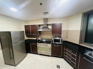 迪拜AlRaef Luxury Apartments的厨房配有不锈钢用具和棕色橱柜