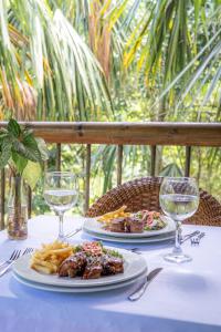 洛斯纳兰霍斯Villa Maria Tayrona, Jungle and Sea Experience的一张桌子,上面放着两盘食物和酒杯