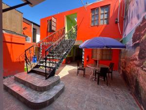 伊基克Hotel Casa del profesor Iquique的楼梯通往带桌子和雨伞的建筑