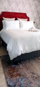 哈博罗内Bakaya Hotel Tlokweng的地毯上一张带白色床单和枕头的床