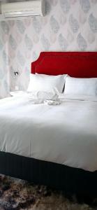 哈博罗内Bakaya Hotel Tlokweng的白色的床,配有红色床头板和白色枕头