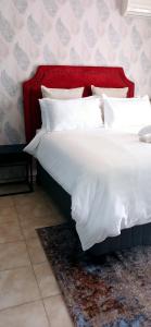 哈博罗内Bakaya Hotel Tlokweng的一张大床,配有红色床头板和白色枕头