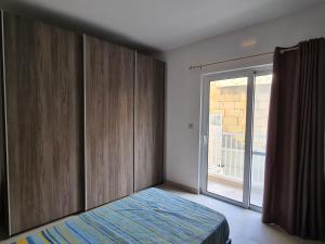 艾因西莱姆Cescaren Gozo Ghajnsielem的一间卧室设有一张床和一个滑动玻璃门