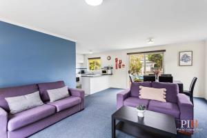 卡尔斯Phillip Island Family Resort 2Bdr的客厅配有两张紫色沙发和一张桌子