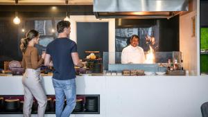 布里斯班voco Brisbane City Centre, an IHG Hotel的男人和女人在厨房里做饭