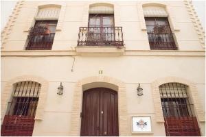 塞维利亚Casa de la Judería Doña Pilar的一座建筑,设有棕色的门和三扇窗户
