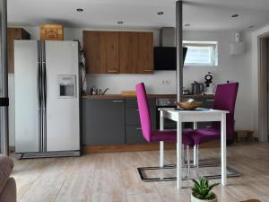 SchmelzMandelas Cozy Lounge的厨房配有冰箱、桌子和紫色椅子