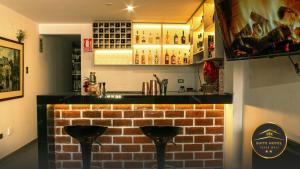 瓦努科YURAQ WASI Hotel/Restobar的砖墙前有两把凳子的酒吧