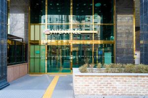 首尔Hotel Aventree Yeouido的一座玻璃建筑,前面有标志