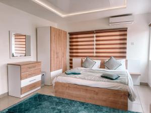 阿克拉Sky Suites East Legon的一间卧室设有一张大床和一个木制床头板