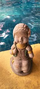清迈兰纳精品度假酒店的坐在游泳池旁的沙子上的雕像