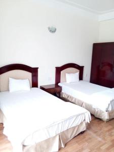 荣市Amazon Hotel的配有白色墙壁和木地板的客房内的两张床