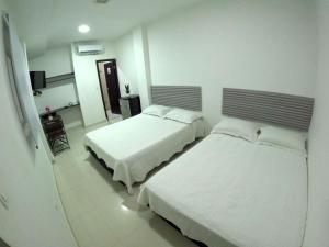 圣安德烈斯Hotel Almendros的一间卧室配有两张床和电视。