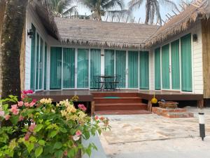 Phumĭ Srê ThmeiNov Koh Kong Resort的一座带绿色窗户、桌子和鲜花的房子