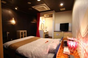 福知山Hotel Mori no Komichi的一间卧室配有一张床和一张桌子及床头柜