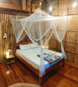 锡基霍尔Kahoy Cottages的一间卧室配有一张带蚊帐的床