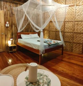 锡基霍尔Kahoy Cottages的一间卧室配有一张床和一张桌子及四柱床