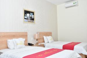 海防Nhà Khách Hương Sen的一间设有两张铺有白色和红色床单的床的客房