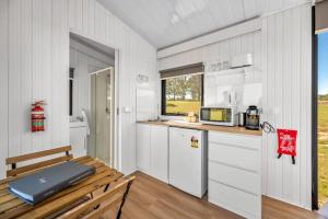 罗斯伯里Valley Escape的厨房配有白色橱柜、桌子和窗户。
