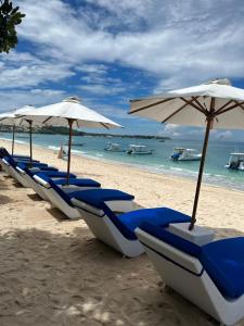 蓝梦岛努沙英达别墅酒店的海滩上一排蓝色的椅子和遮阳伞