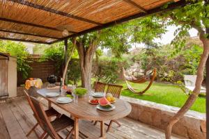 卡尔维Very warm villa "Acacia" with beautiful garden - 4 6 people的木制凉棚下的木桌和椅子